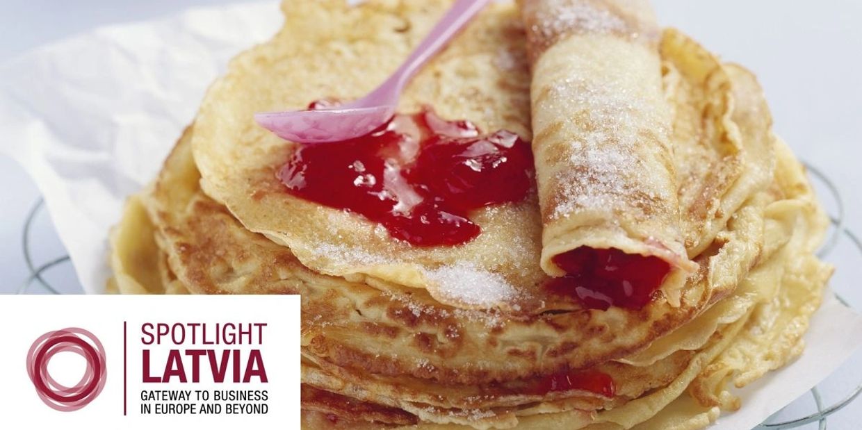 Stack of Latvian pancakes with red jam and sugar on top.