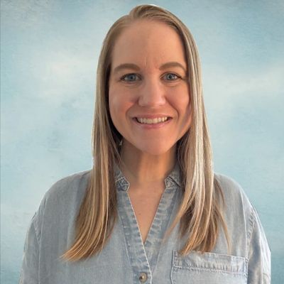Smiling woman with long blonde hair in denim shirt.