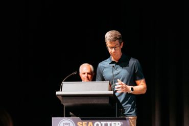 Man standing at a podium on a dark stage.