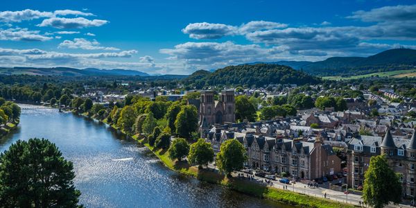 Aerial view of Inverness with the River Ness flowing through the city, surrounded by hills.
