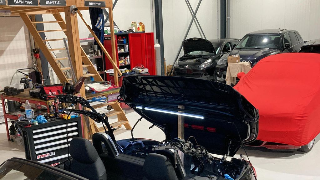 Car repair garage with a convertible car and various vehicles.