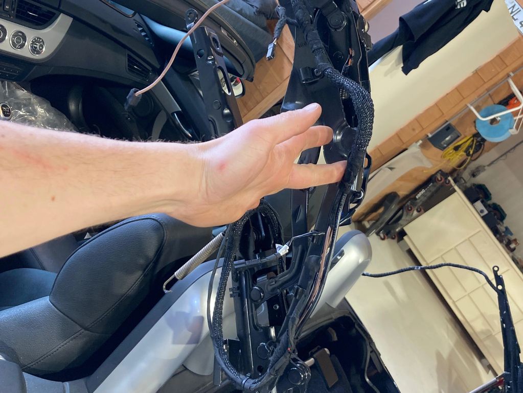 Hand holding a car door wiring harness inside a vehicle.