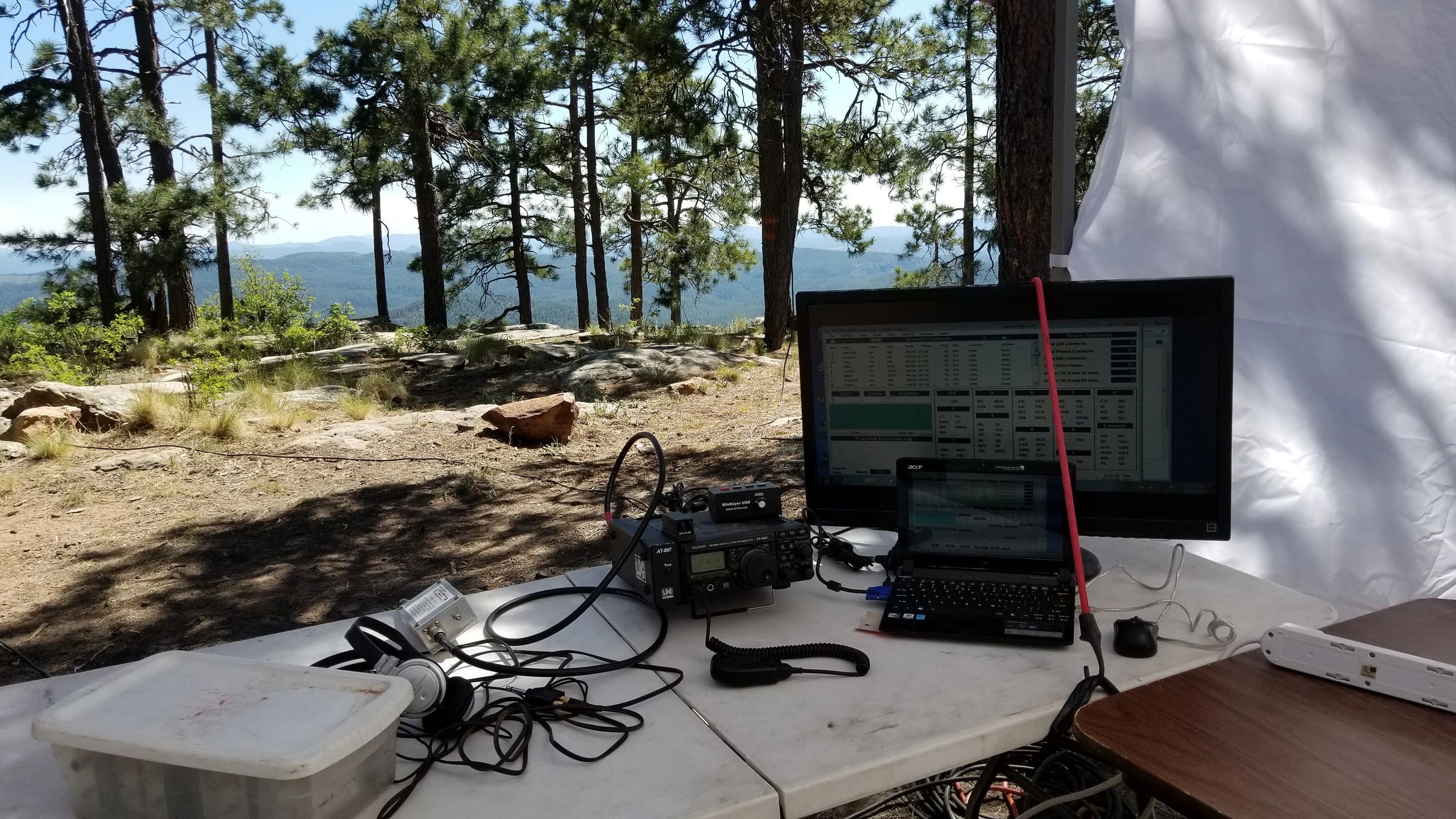 Portable radio communication setup in a forested mountain area with laptops and equipment.