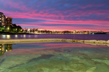 Golden hour photography over reflective Fairy Bower pool, Manly Beach, Sydney, Australia city lights
