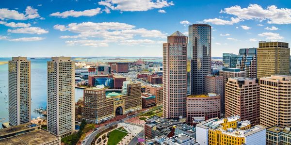 A panoramic view of a vibrant city skyline with tall buildings, waterfront, and a clear blue sky