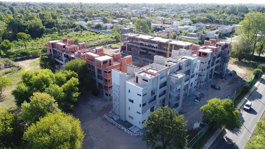 Edificio en construcción visto desde arriba, rodeado de árboles.