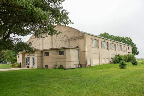 Exterior view of a beige community center building surrounded by grass and trees.