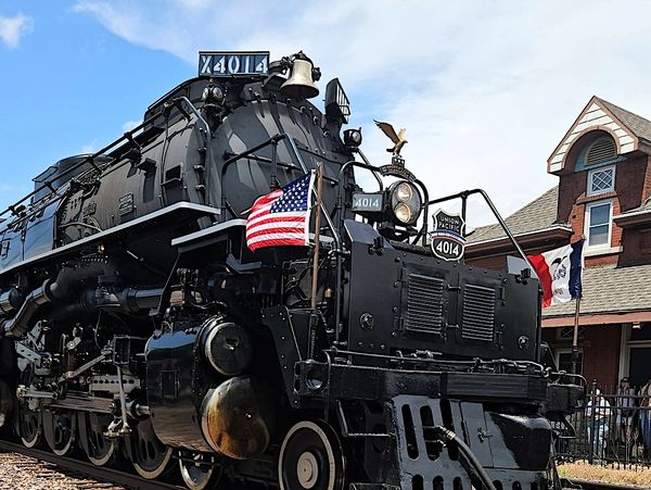 Historic Union Pacific steam locomotive 4014 with American flag at a train station.