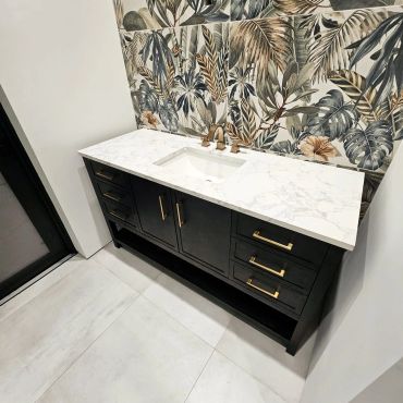 Modern black vanity with white marble countertop and tropical wallpaper.