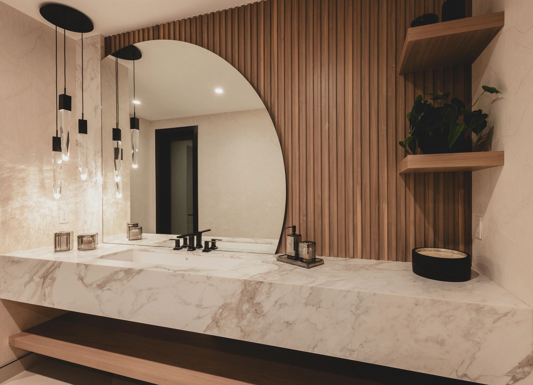 Modern bathroom with marble countertop and unique round mirror.