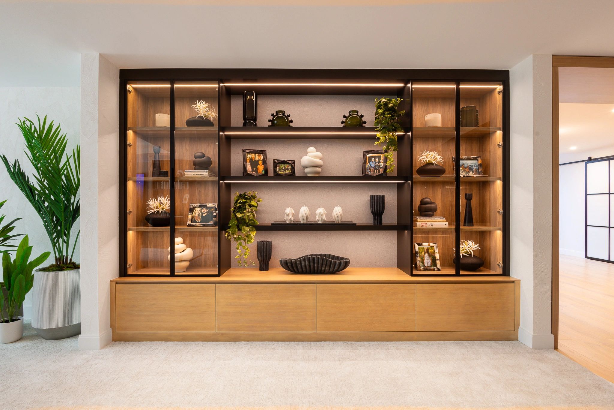 Modern wooden cabinet with glass doors, decorative items, and family photos.