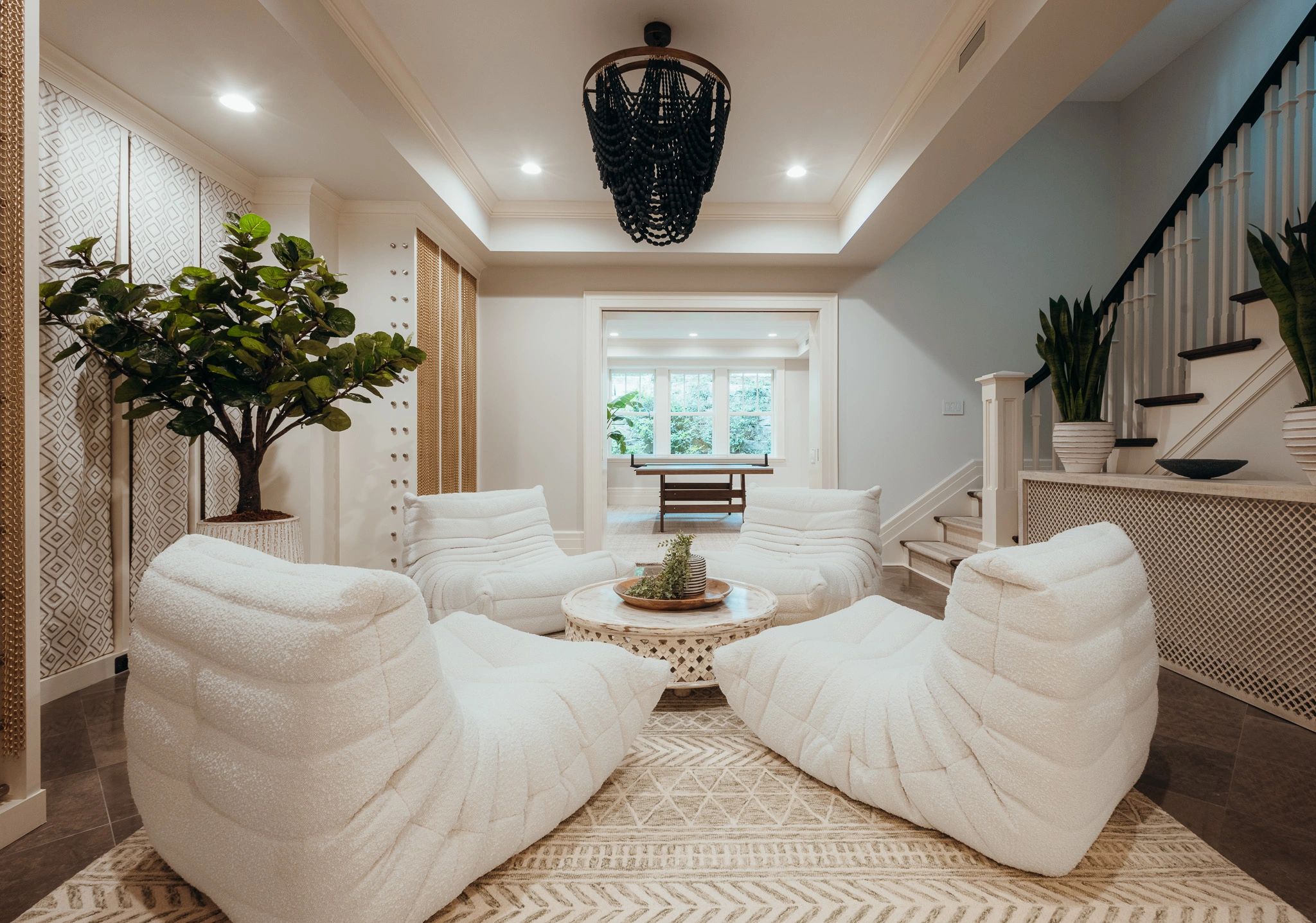 Cozy modern living room with plush white chairs and greenery.