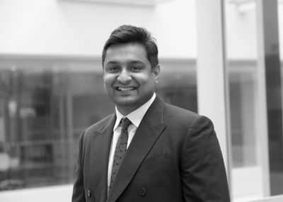 Smiling man in a suit and tie in an office setting.