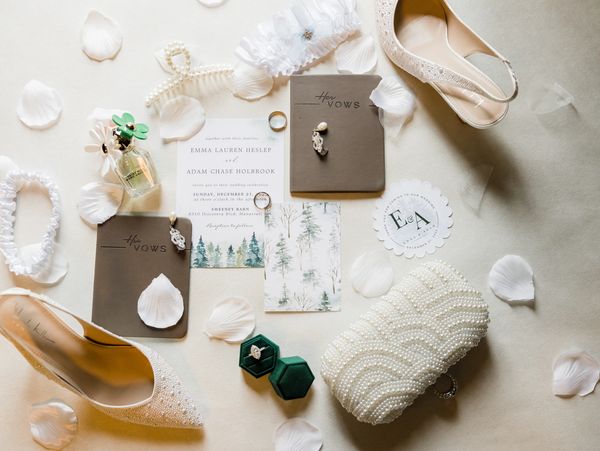 Wedding accessories and invitations arranged on a beige surface.