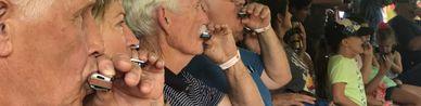 A row of workshop attendees playing harmonica