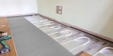 Underfloor heating pipes being installed before floor covering.