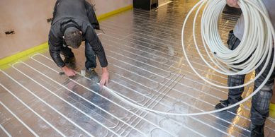 Workers installing underfloor heating pipes.
