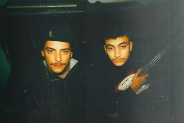 Two young men posing with a musical instrument in a dimly lit room.