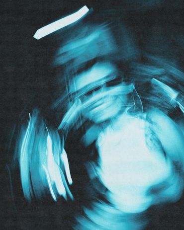 Blurred, blue-toned motion portrait of a person wearing sunglasses.