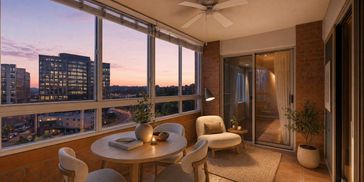 Cozy balcony with seating and sunset city view.