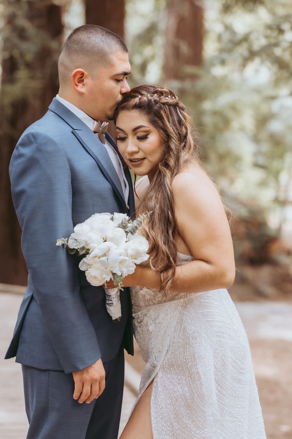 Bride and groom share a tender moment outdoors on their wedding day.