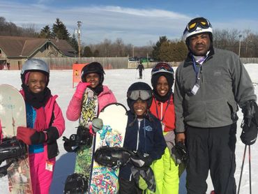 Group of youth and adult holding snowboards/skiing.