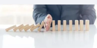 Hand stopping falling dominoes.