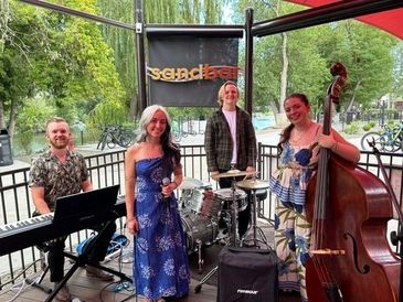 A lively outdoor jazz band performing with smiles and instruments.