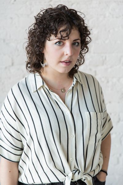 Young woman with curly hair wearing a striped shirt.