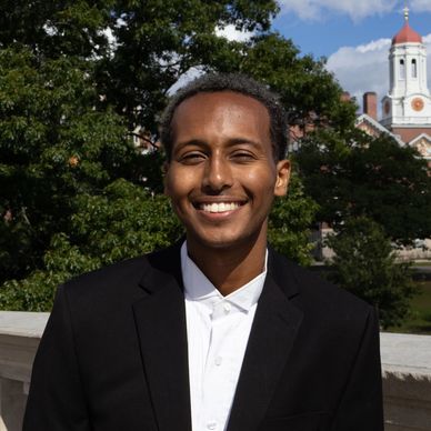Young man smiling outdoors in formal attire.