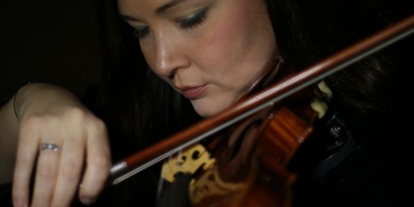 A woman deeply focused while playing a violin.