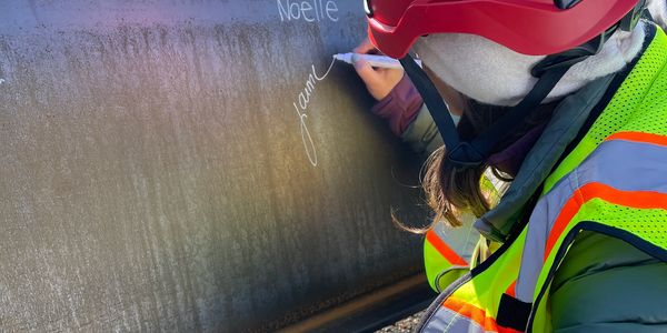Jaime Clark, ArmourSash Founder, signing a beam at a high school topping out celebration.