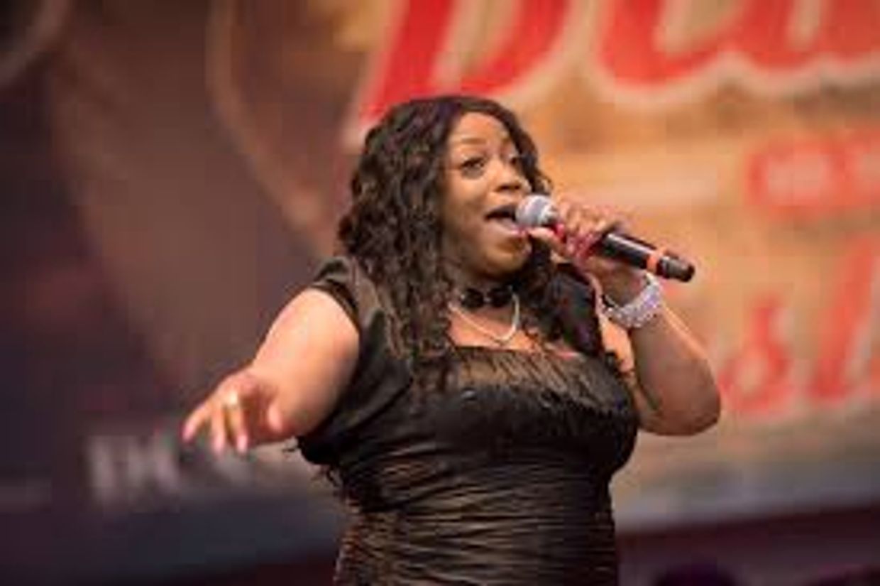 Woman passionately singing on stage with a microphone.
