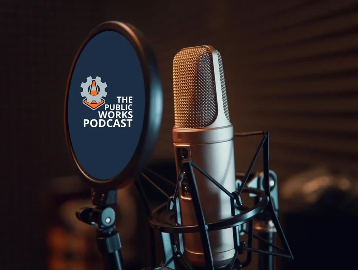 Professional podcast microphone setup with pop filter displaying 'The Public Works Podcast' logo.