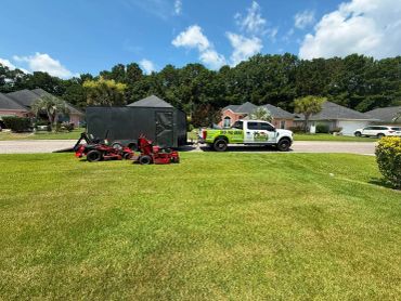 Truck and lawnmowers on a suburban lawn.