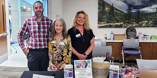 Three representatives stand behind an informational table for Above & Beyond Senior Living.