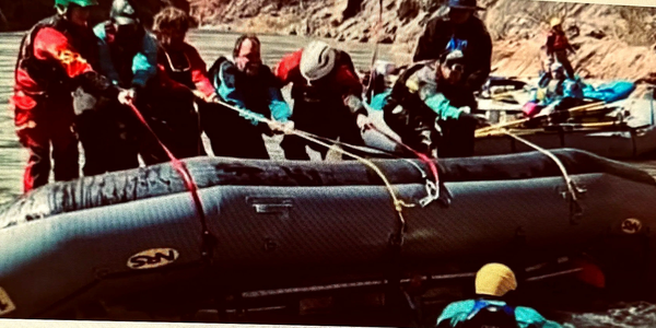 Group of people preparing a raft on a river for rafting.