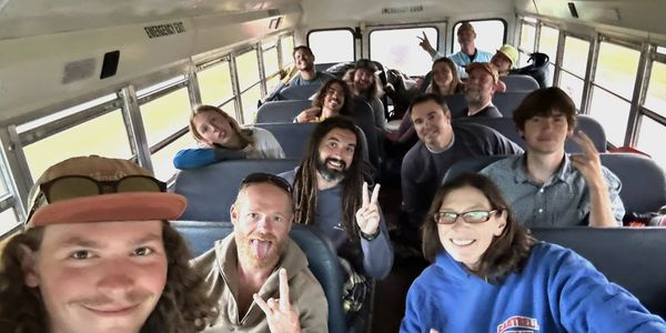 Group of friends smiling and making peace signs inside a bus.