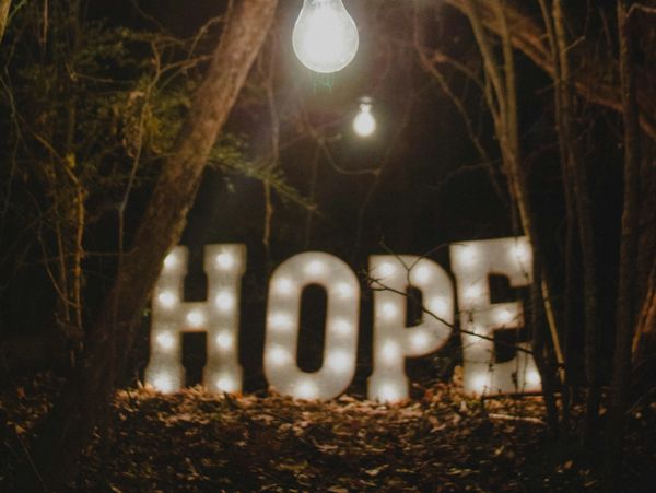Illuminated HOPE letters glowing in a dark forest at night.