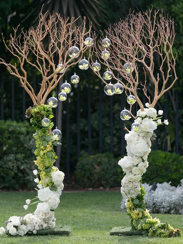 Archway built from manzanita trees dressed with flowers and glass bubbles for an outdoor wedding.