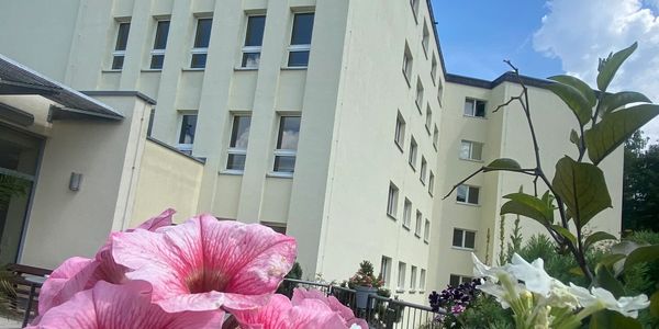 Außenansicht des Wohnparks "Alte Klinik" mit Blumen im Vordergrund