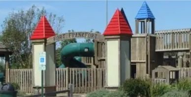 Playground structure named Fort Frankfort with red and blue peaked roofs.