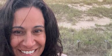Smiling woman with a grassy background.