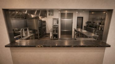 Modern industrial kitchen seen through a pass-through window.