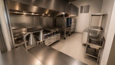 Clean and empty commercial kitchen with stainless steel appliances.