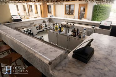 Modern outdoor bar with marble countertops and beverage setup.