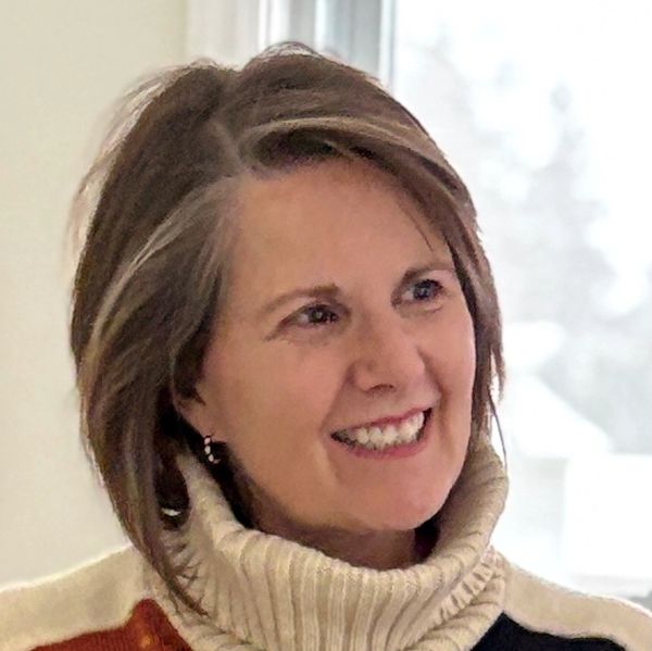 Smiling woman with short hair wearing a cozy turtleneck sweater.