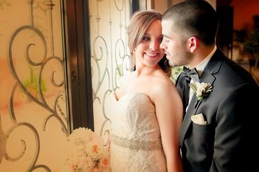 Newlyweds share an intimate moment by a window.
