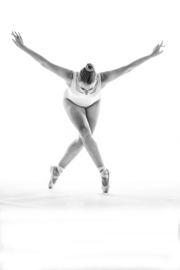 Ballet dancer in a balanced pose with arms outstretched.