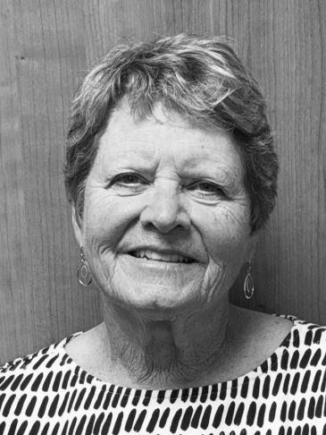 Smiling elderly woman with short hair and patterned top.